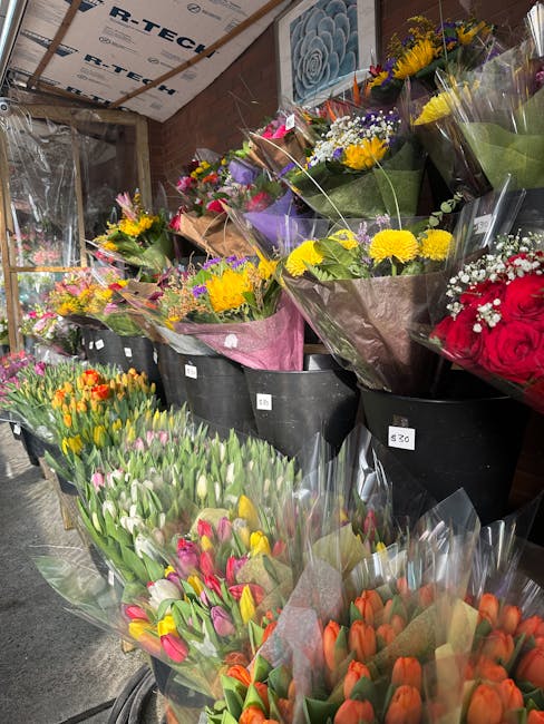 A display of freshly arranged flower bouquets at a flower shop, featuring a variety of colorful blooms including tulips in shades of pink, orange, and white, along with sprays of yellow daisies, purpl
